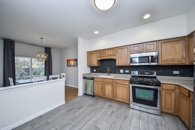 kitchen with sink, decorative light fixtures, appliances with stainless steel finishes, light hardwood / wood-style floors, and backsplash