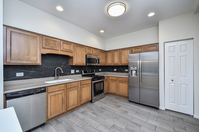 kitchen with appliances with stainless steel finishes, sink, backsplash, and light wood-type flooring