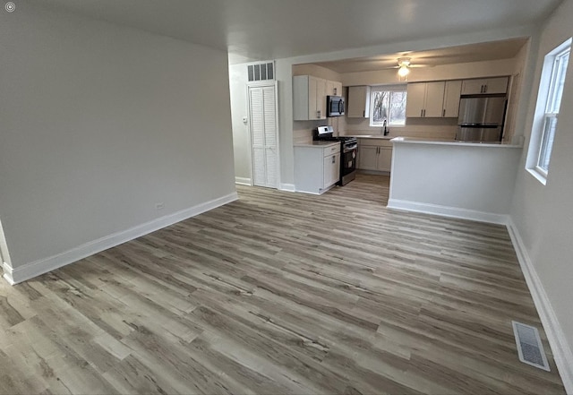 kitchen with sink, white cabinetry, ceiling fan, stainless steel appliances, and light hardwood / wood-style floors