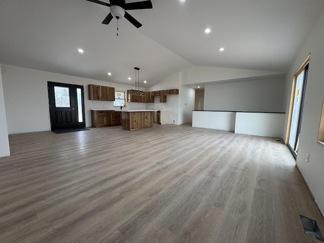 unfurnished living room featuring lofted ceiling, visible vents, a ceiling fan, a sink, and light wood-style floors