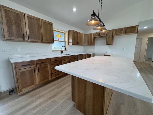 kitchen with lofted ceiling, a sink, a center island, light wood-style flooring, and hanging light fixtures