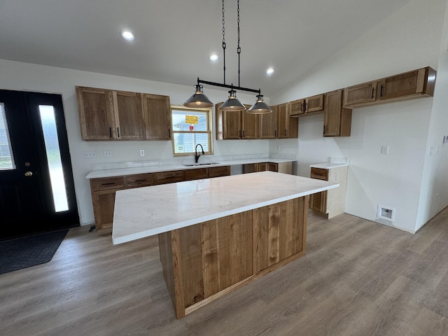 kitchen featuring wood finished floors, a center island, pendant lighting, and a sink