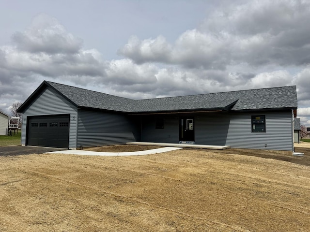 ranch-style house featuring an attached garage, a shingled roof, and aphalt driveway