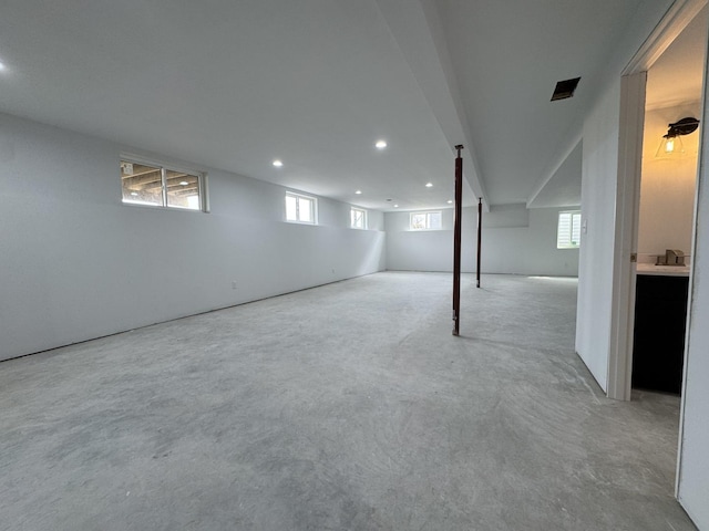below grade area with plenty of natural light, carpet floors, a sink, and recessed lighting