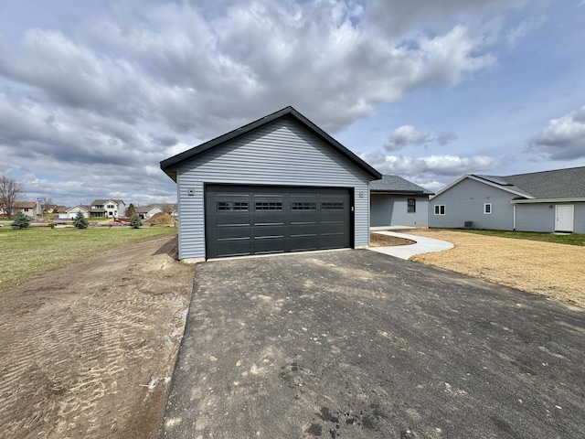 exterior space featuring aphalt driveway, a front lawn, and an outbuilding