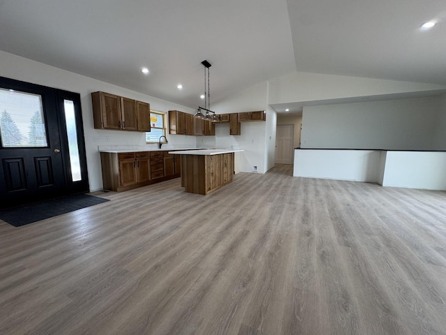kitchen with lofted ceiling, a center island, open floor plan, and light wood-style flooring