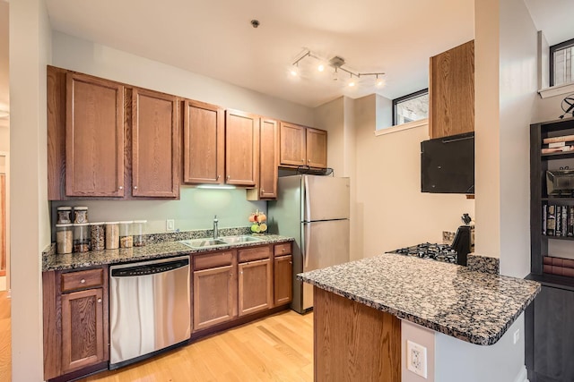 kitchen with appliances with stainless steel finishes, sink, dark stone countertops, and kitchen peninsula