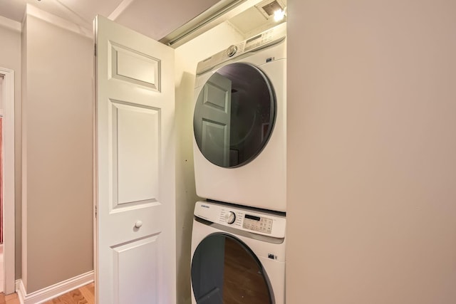 laundry room featuring stacked washing maching and dryer and light hardwood / wood-style floors