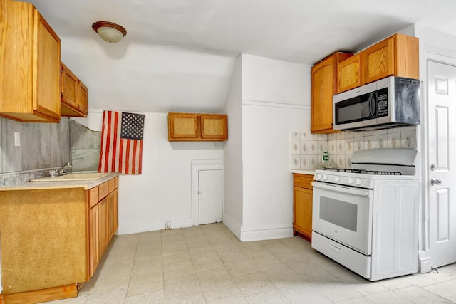 kitchen with tasteful backsplash, vaulted ceiling, sink, and white gas range oven