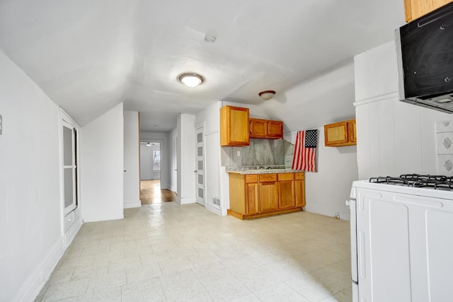 kitchen with white gas range, vaulted ceiling, and decorative backsplash