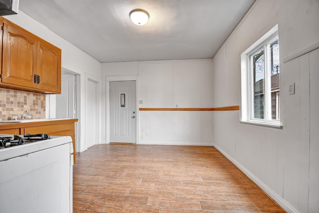 kitchen featuring white gas range oven, light hardwood / wood-style flooring, and backsplash