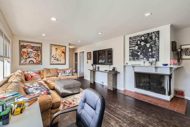 living room with a brick fireplace and dark hardwood / wood-style floors