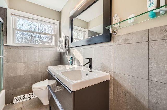 bathroom with tile walls, vanity, tile patterned floors, and toilet