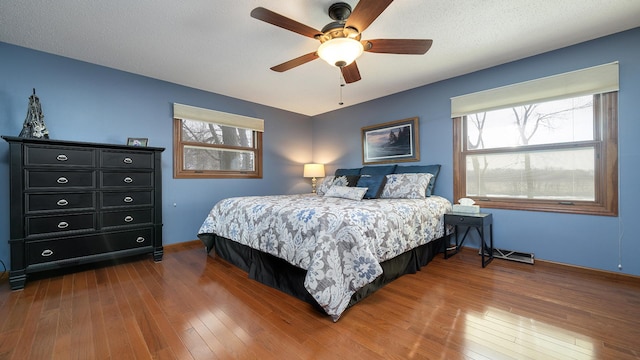 bedroom with multiple windows, hardwood / wood-style floors, and ceiling fan