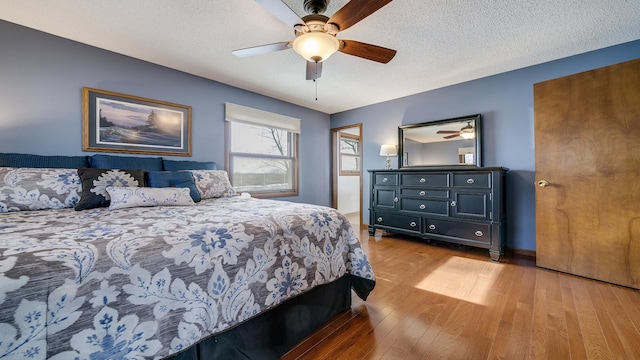 bedroom with ceiling fan, hardwood / wood-style floors, and a textured ceiling