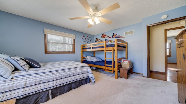 bedroom featuring ceiling fan, light colored carpet, and a textured ceiling