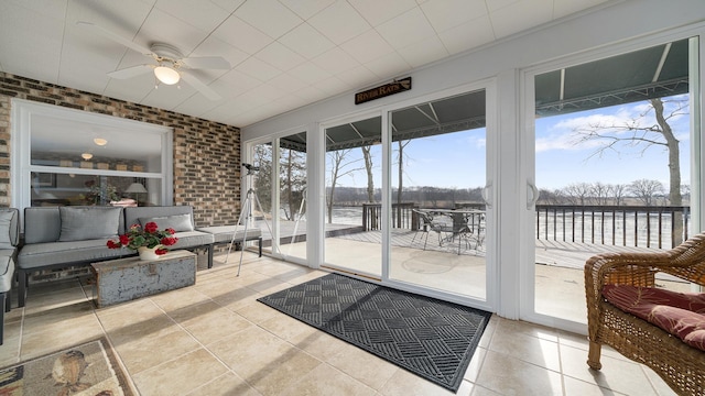 sunroom with ceiling fan and a water view