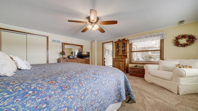 carpeted bedroom with ceiling fan and a textured ceiling