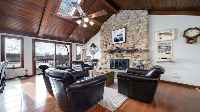 living room with wood ceiling, hardwood / wood-style flooring, a skylight, a stone fireplace, and beamed ceiling