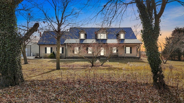 new england style home with metal roof and a yard