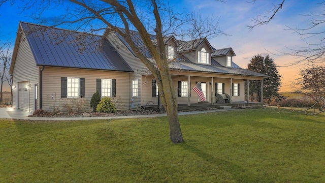 cape cod home with driveway, covered porch, a front lawn, and metal roof