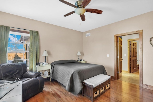 bedroom featuring light wood finished floors, baseboards, visible vents, and a ceiling fan