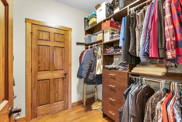 walk in closet with light wood-style floors