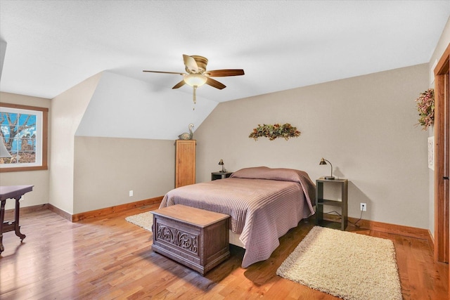 bedroom featuring lofted ceiling, light wood-style flooring, baseboards, and a ceiling fan