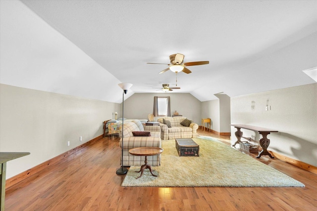 living area with vaulted ceiling, baseboards, a ceiling fan, and light wood-style floors