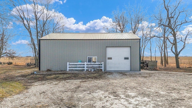 detached garage with a rural view and fence