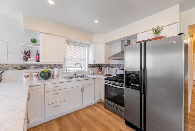 kitchen with white cabinetry, appliances with stainless steel finishes, sink, and wall chimney range hood