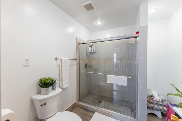 bathroom featuring hardwood / wood-style flooring, toilet, and a shower with door