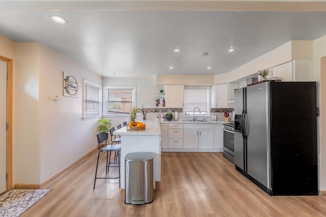 kitchen with a breakfast bar, a kitchen island, white cabinets, stainless steel appliances, and backsplash