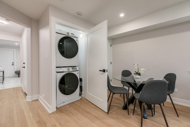 laundry area with light hardwood / wood-style flooring and stacked washing maching and dryer