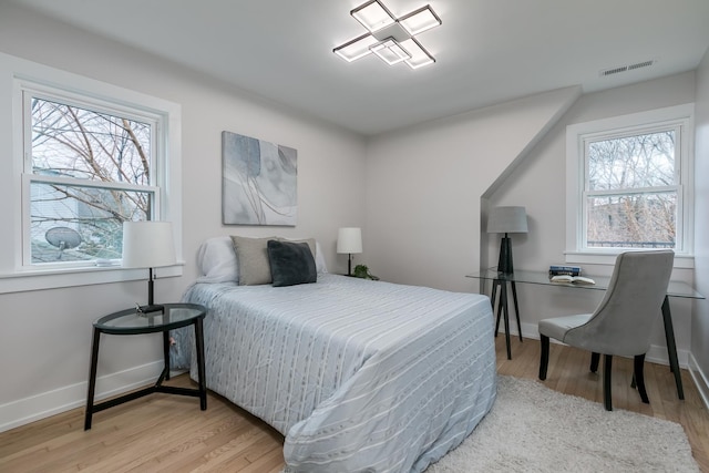 bedroom with multiple windows and light hardwood / wood-style flooring