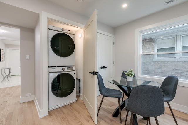 laundry area with stacked washer and dryer and light hardwood / wood-style floors