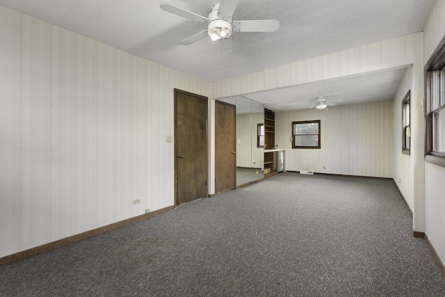 spare room with ceiling fan, a textured ceiling, and dark colored carpet