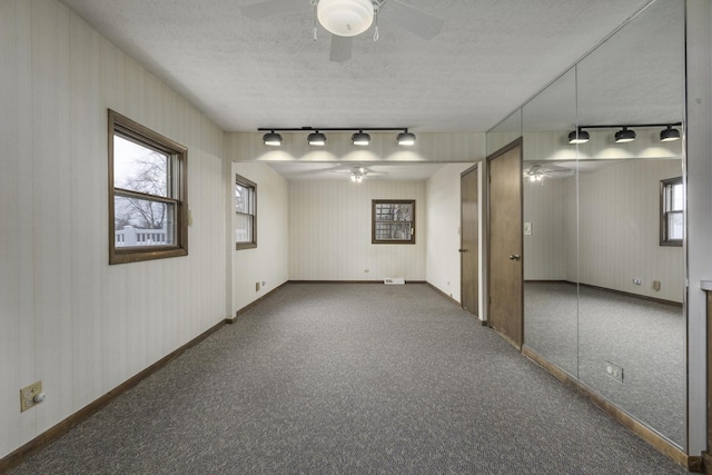 empty room with dark carpet, a textured ceiling, and ceiling fan