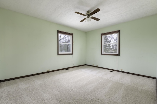 empty room with ceiling fan, light carpet, and a textured ceiling