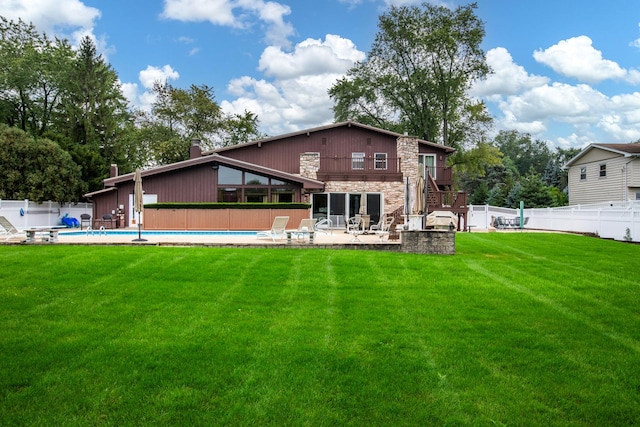 rear view of property with a fenced in pool, a yard, a patio area, and a balcony