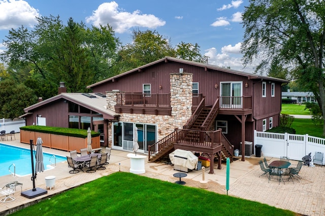 back of property featuring a fenced in pool, a patio, a balcony, and a lawn