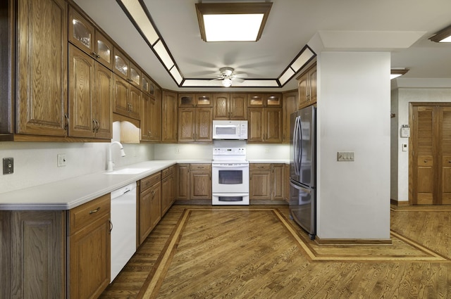 kitchen with sink, dark hardwood / wood-style flooring, ceiling fan, a raised ceiling, and white appliances