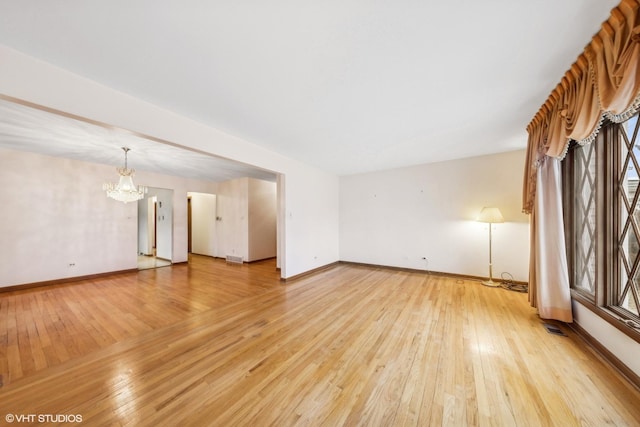 unfurnished living room with an inviting chandelier and light wood-type flooring