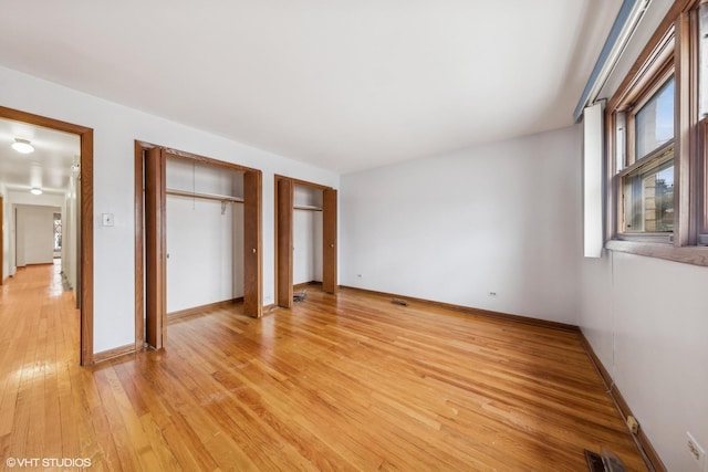 unfurnished bedroom with multiple closets and hardwood / wood-style floors