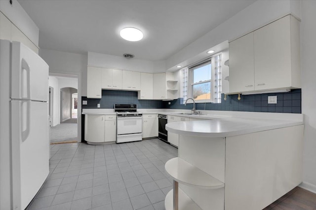 kitchen featuring sink, kitchen peninsula, white cabinets, white appliances, and backsplash