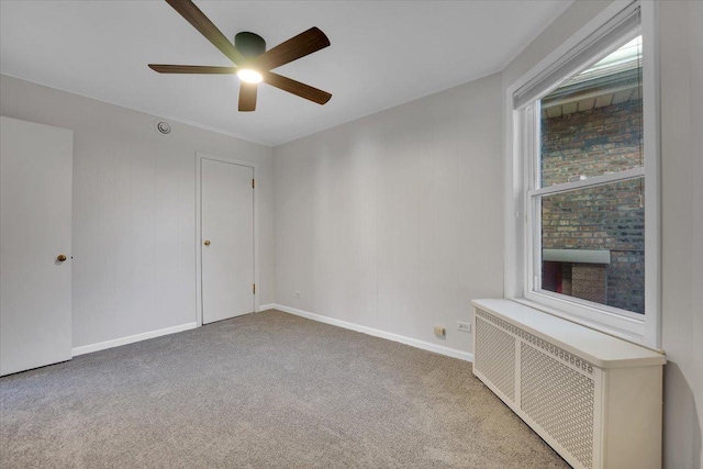 unfurnished room featuring ceiling fan, carpet flooring, and radiator