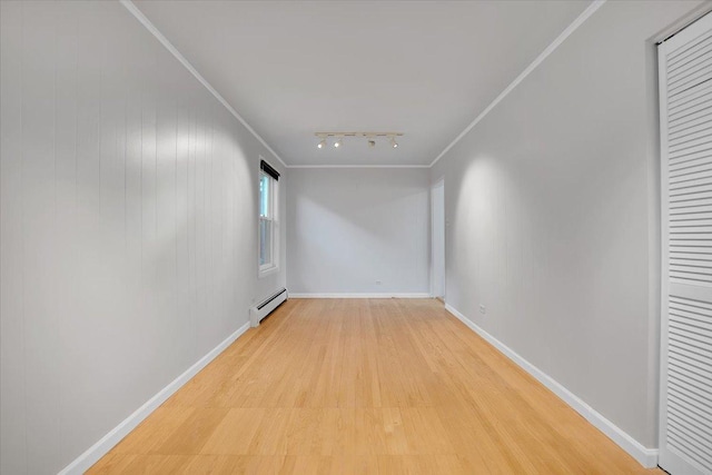 spare room with light wood-type flooring, crown molding, track lighting, and baseboard heating