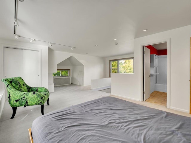 unfurnished bedroom featuring ensuite bath, light colored carpet, and rail lighting