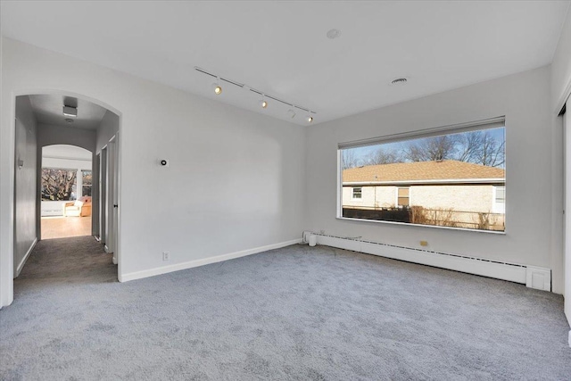 carpeted empty room featuring a baseboard radiator and track lighting