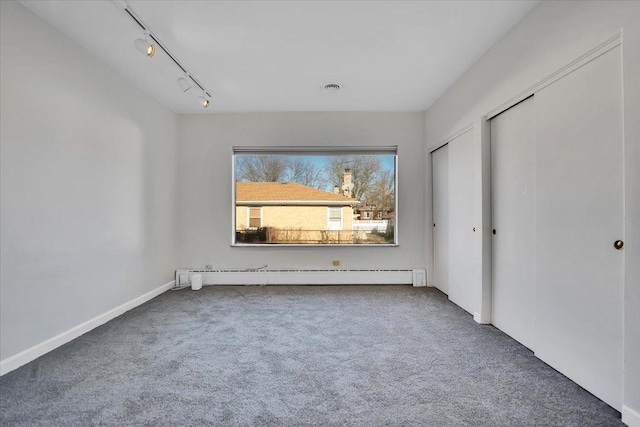 unfurnished bedroom with a baseboard radiator, rail lighting, and carpet